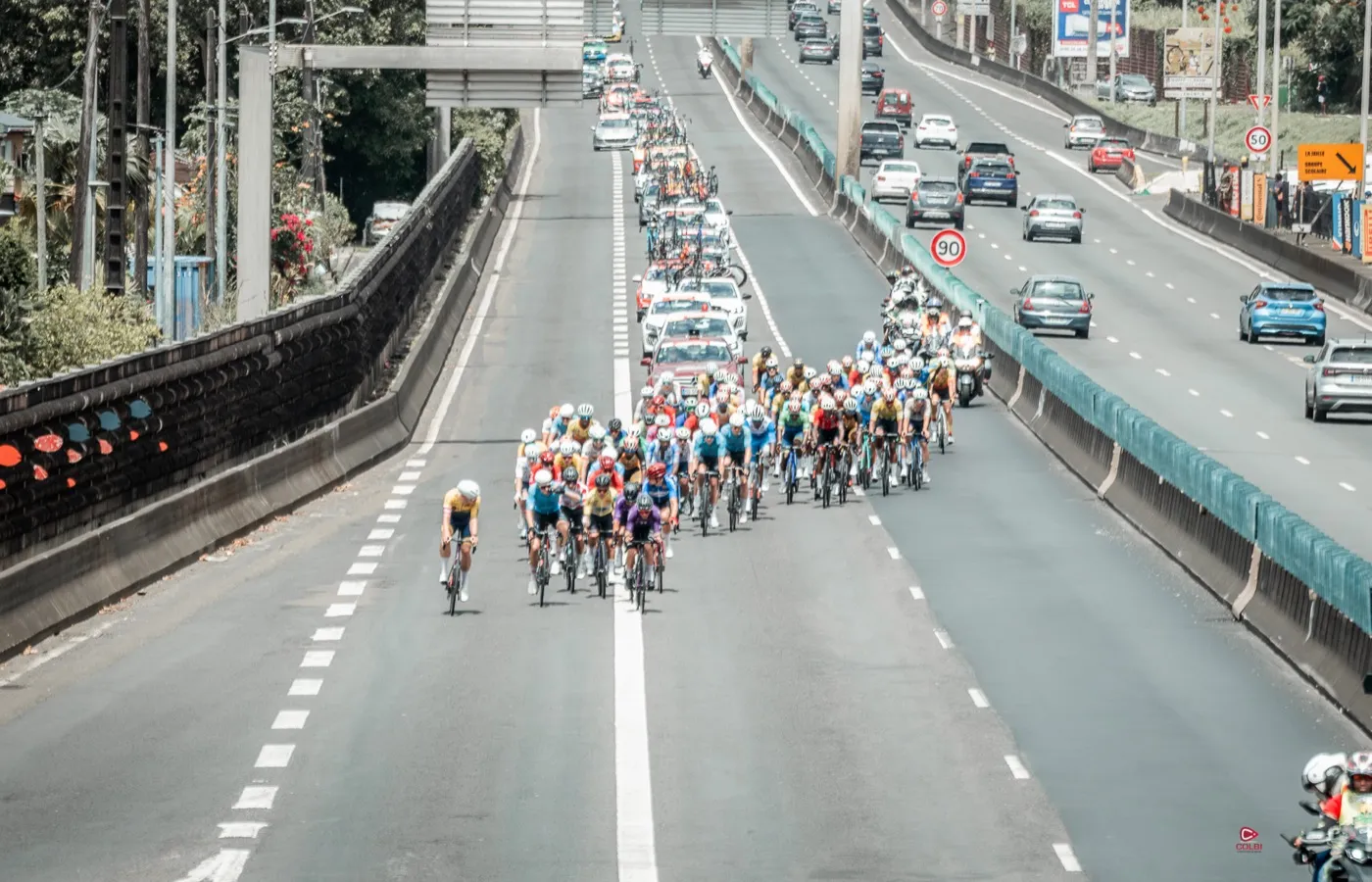 Le peloton du Tour cycliste de la Guadeloupe déployé sur la rocade fermée à la circulation, entouré des véhicules officiels