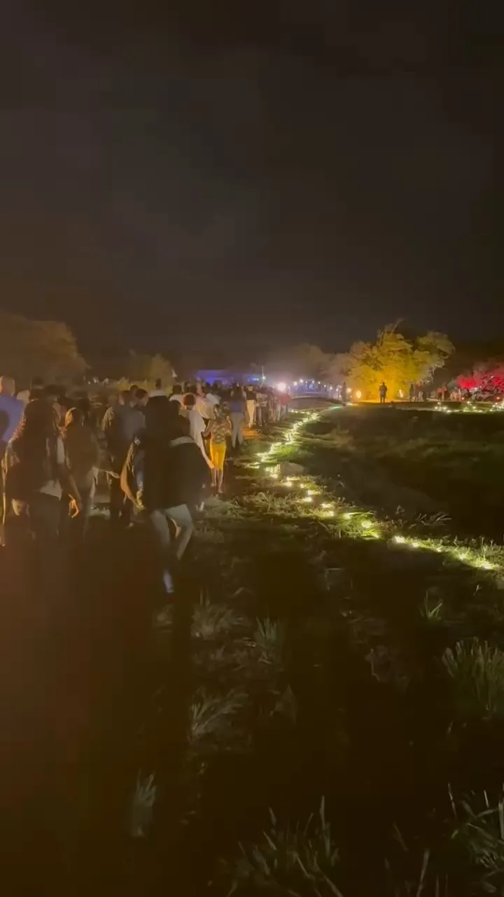 De nuit, la foule d’un événement rejoint la scène par un cheminement balisé de lumières au sol.